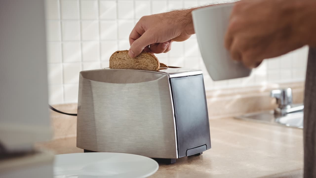 hombre-tostando-pan-para-el-desayuno-y-tomando-cafe hombre-tostando-pan-para-el-desayuno-y-tomando-cafe